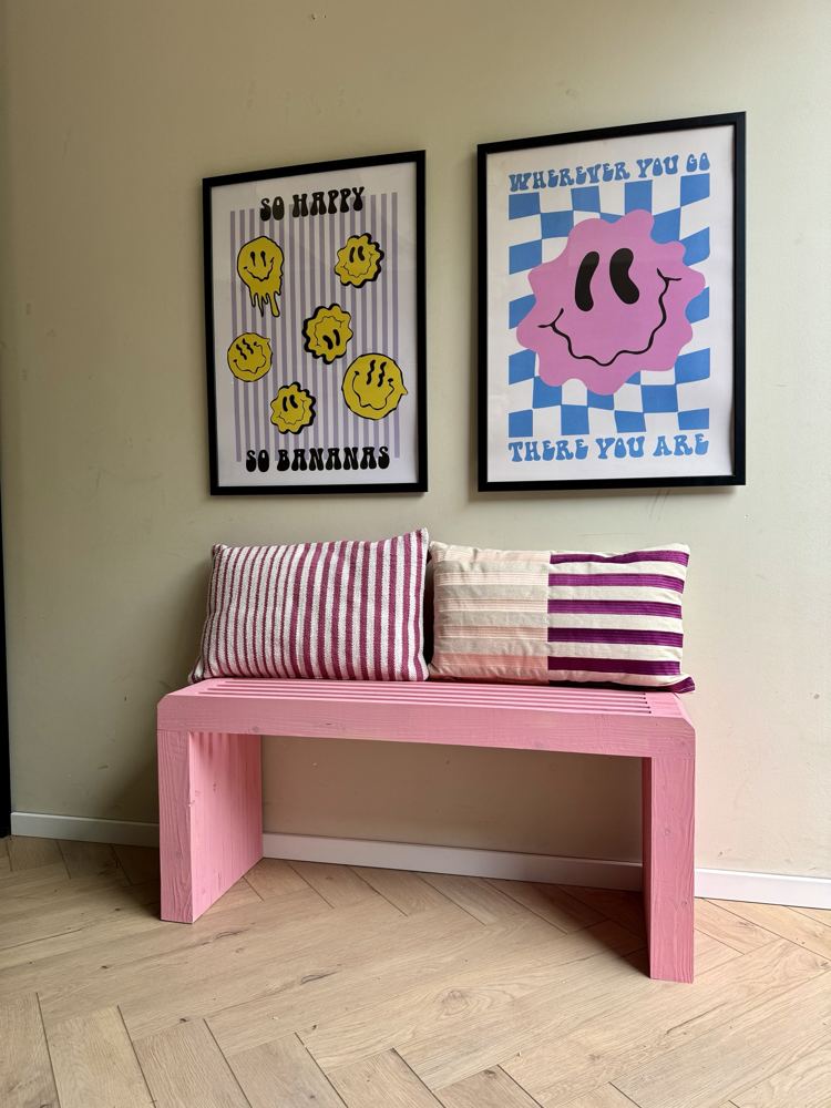 Roze geverfd bankje onder twee posters